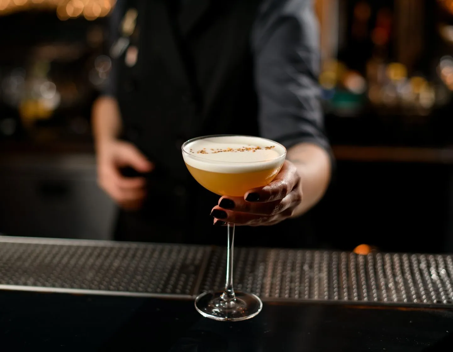 Bartender segurando um coquetel com espuma numa taça coupe