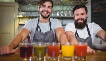 Dois bartenders sorrindo atrás de drinques