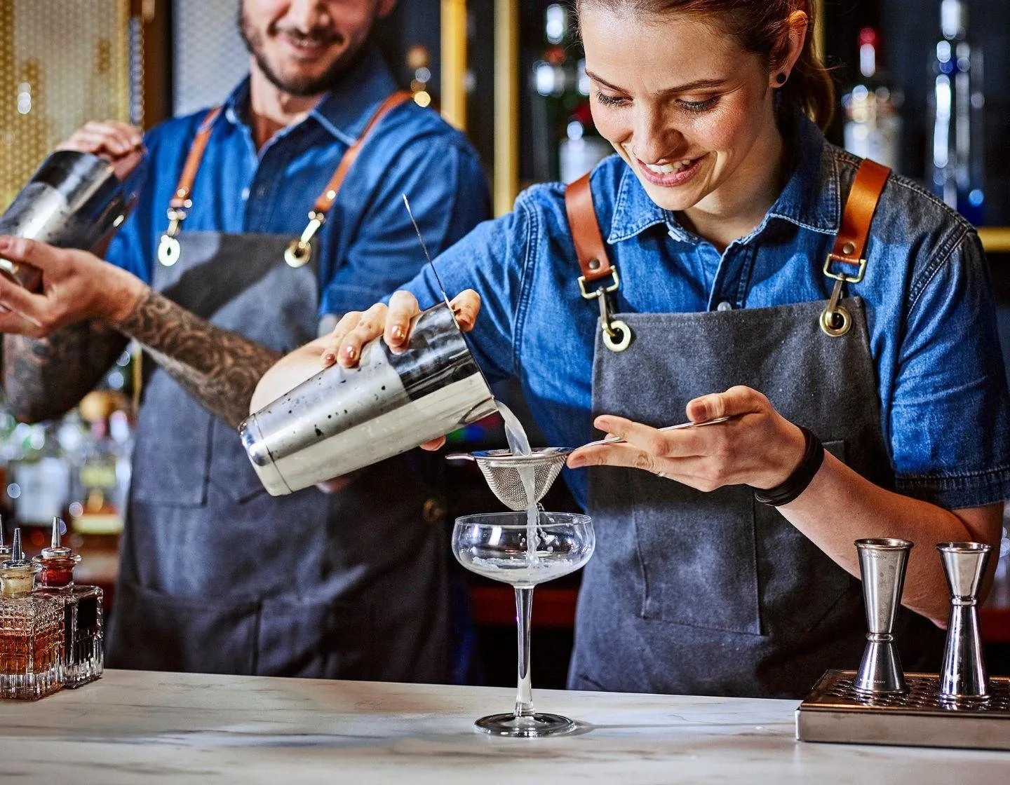 Dois bartenders servindo coquetéis no balcão