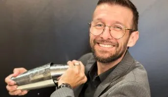André Bueno, treinador do Diageo Bar Academy, sorrindo atrás do balcão