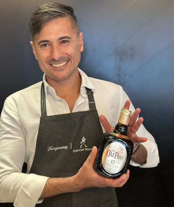 Marcelo Prantoni de avental segurando uma garrafa de Old Parr 12 anos