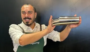 Henrique Abrahão, treinador do Diageo Bar Academy, sorrindo atrás do balcão