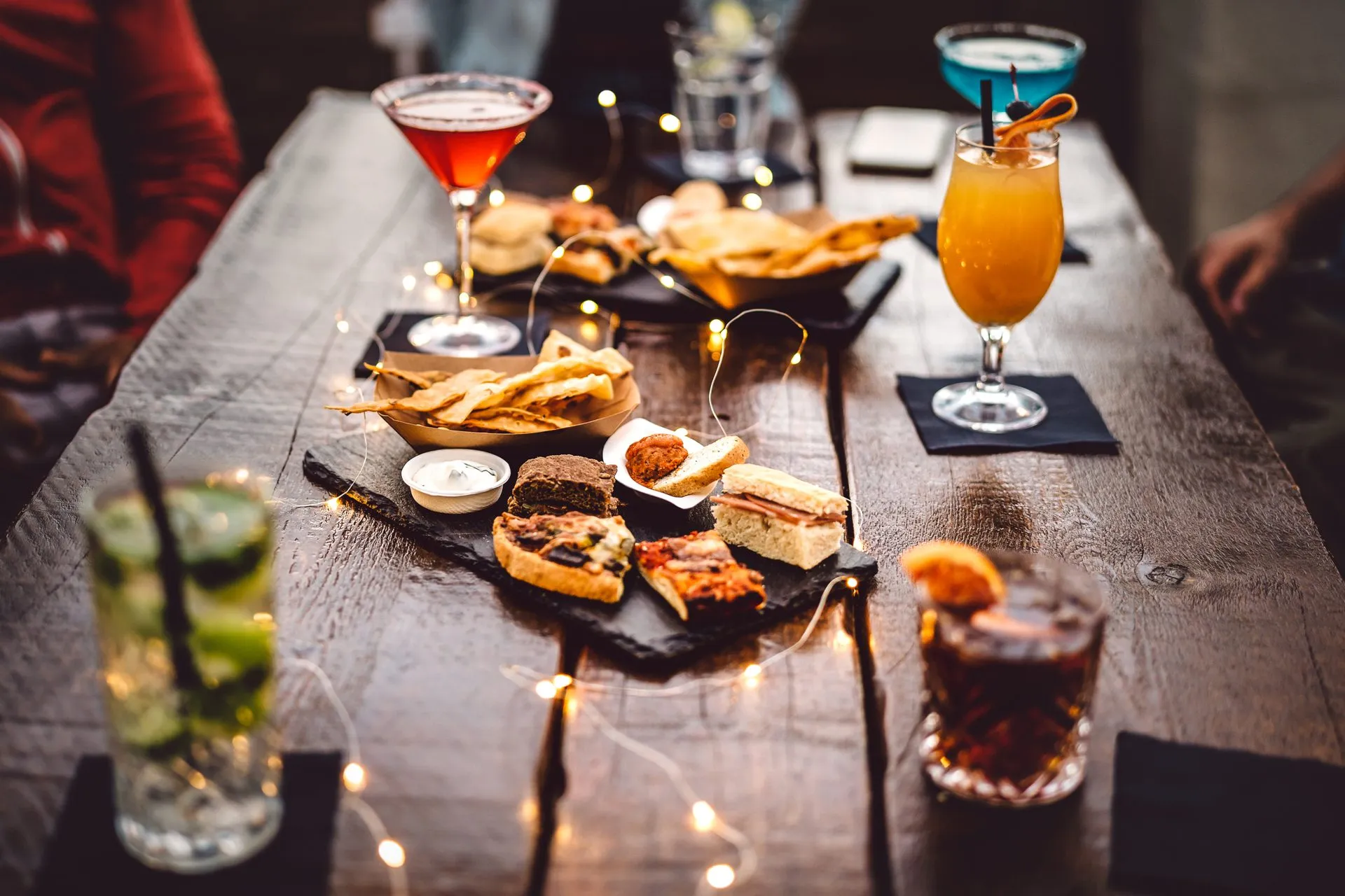 Mesa de bar com coquetéis, petiscos e luzes