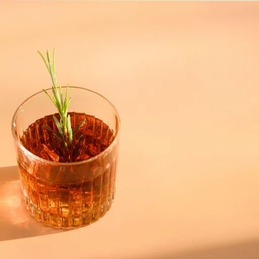 Copo de Whisky com gelo e guarnição de alecrim