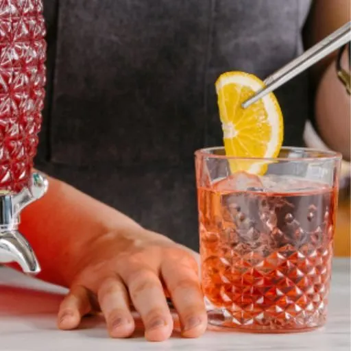 Bartender using lemon garnish to create the perfect red coloured cocktail