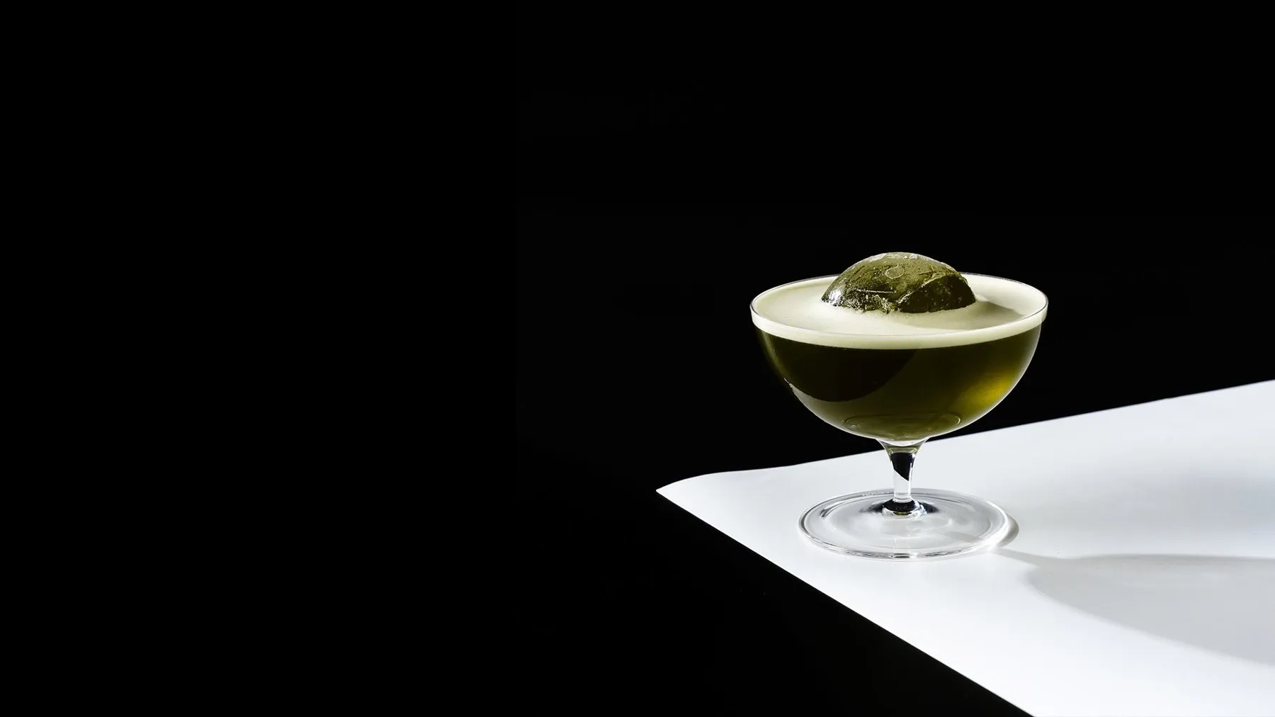 Coquetel verde com gelo esférico em taça coupe